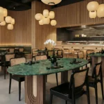 Restaurant with Nolita Harbour tables, the emerald green marble Emerald dining table, conceived as a sculptural volume that anchors dining spaces with quiet authority.