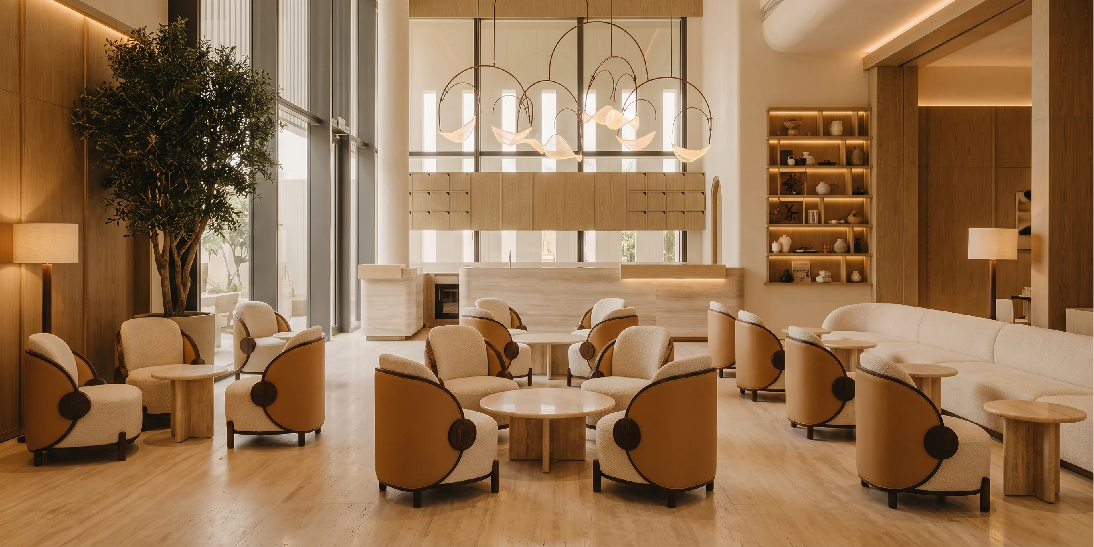 Luxury Nolita Harbour lounge with Marie bouclé armchairs, sculptural walnut frames, grand chandeliers, and refined contemporary interior design.
