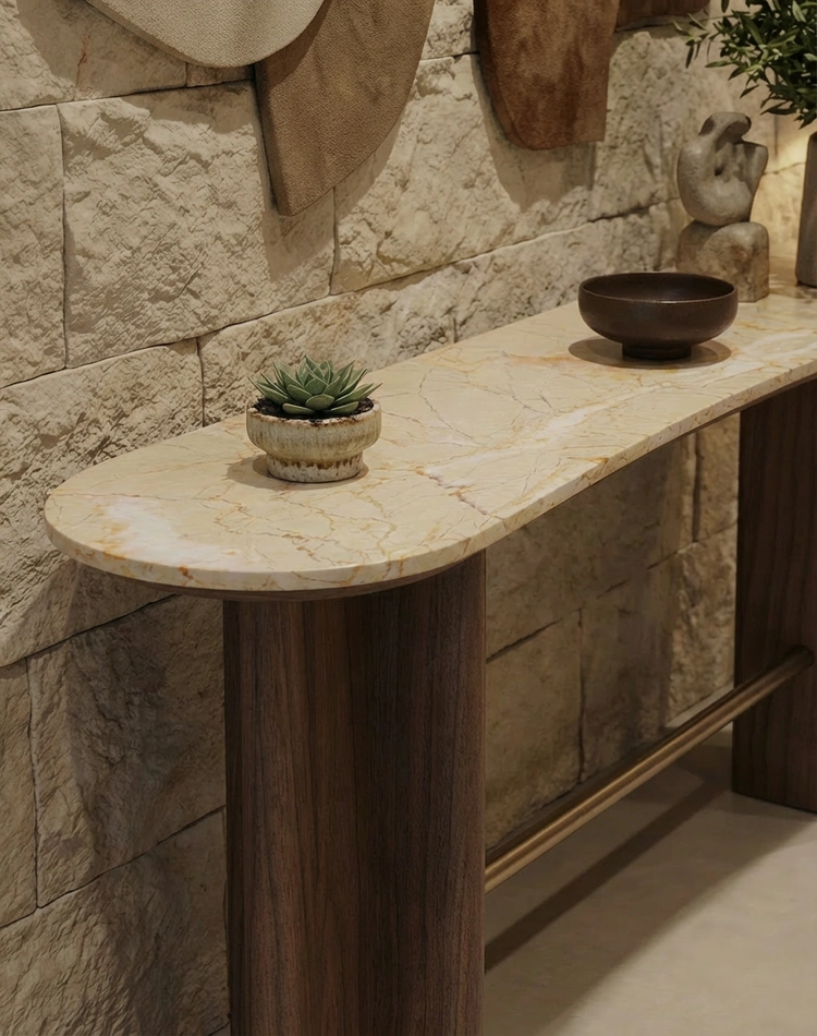 The Romi console, by Nolita Harbour, showcasing its honed stone top and refined walnut legs, leaned against a stone wall.