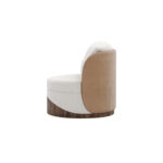 Round luxury armchair with cream fabric, beige accents, and a walnut wood wavy base, featuring a plush cushion, designed by Nolita Harbour. Side view