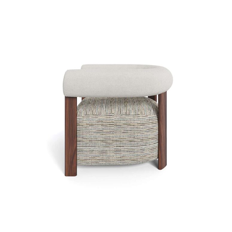 Modern luxury armchair with rounded cushioned backrest, neutral upholstery, patterned fabric seat, and walnut legs, designed by Nolita Harbour. side view