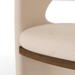 Beige luxury dining chair with a curved open-back design, linen upholstery, and walnut accent detail by Nolita Harbour. detail view