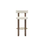 Odette upholstered bar chair by Nolita Harbour, bouclé seat with walnut legs and brass footrest, elegant modern design.
