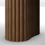 A detailed view of teh Santi Dining Table, a refined dining table by Nolita Harbour that combines travertine top, ribbed walnut base, and brass accents.