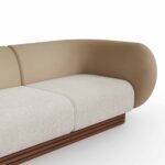 Curved sectional sofa with taupe leather upholstery, cream fabric seat cushions, and a walnut base, designed by Nolita Harbour. detail view