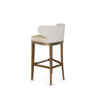 Elegant bar chair with a curved upholstered backrest, beige cushioned seat, and walnut wood legs with metal accents, designed by Nolita Harbour for modern bar settings. 45 degree back view