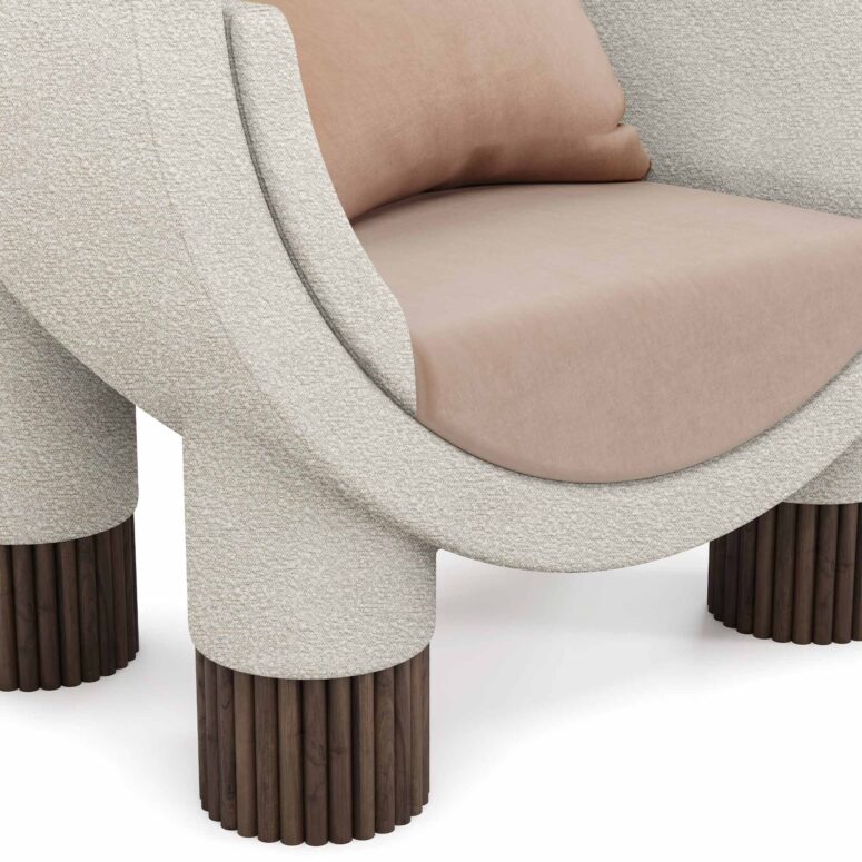 Modern armchair with a curved frame, upholstered in soft fabric, featuring ribbed walnut legs, and plush beige cushions, by Nolita Harbour. Anna Armchair 45 detail view