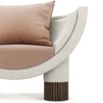 Modern armchair with a curved frame, upholstered in soft fabric, featuring ribbed walnut legs, and plush beige cushions, by Nolita Harbour. Anna Armchair 45 detail view