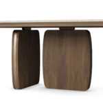 Assia Oval dining table with a smooth travertine tabletop and sculptural walnut legs, crafted by Nolita Harbour.