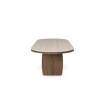 Assia Oval dining table with a smooth travertine tabletop and sculptural walnut legs, crafted by Nolita Harbour.