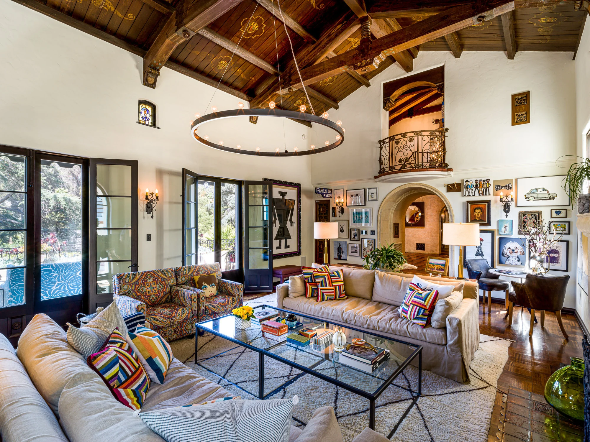 A vibrant Mediterranean-style living room with exposed wooden beams, colorful patterned cushions, and an eclectic mix of artwork. The space features a mix of classic and contemporary elements, creating a warm and inviting atmosphere. - Nolita Harbour