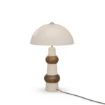 Claus Table Lamp, a sculptural table lamp by Nolita Harbour in travertine, walnut, and dome shade, casting a warm glow.
