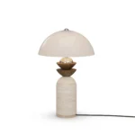 Gustav Table Lamp, a sculptural table lamp by Nolita Harbour in travertine, walnut, and a dome shade, casting a soft glow.