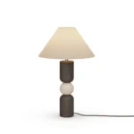 Luuk Table Lamp, a sculptural table lamp by Nolita Harbour in black wood, travertine, and fabric shade, casting a warm glow.