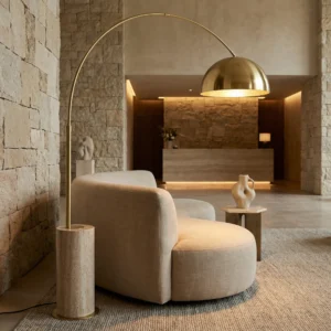 Hotel lobby with a sofa and Nils floor lamp, by Nolita Harbour, set against a stone all, showcasing a luxurious and warm hospitality.
