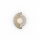 Noemi Wall Lamp wall light by Nolita Harbour in Estremoz marble, brushed metal, and opal glass globe, sculptural compact design casting soft ambient glow on textured stone surface.