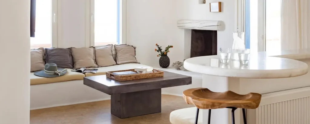 Villa Aegean Horizon Mykonos interior with minimalist white design, built-in sofa, rustic wooden accents, and natural light.