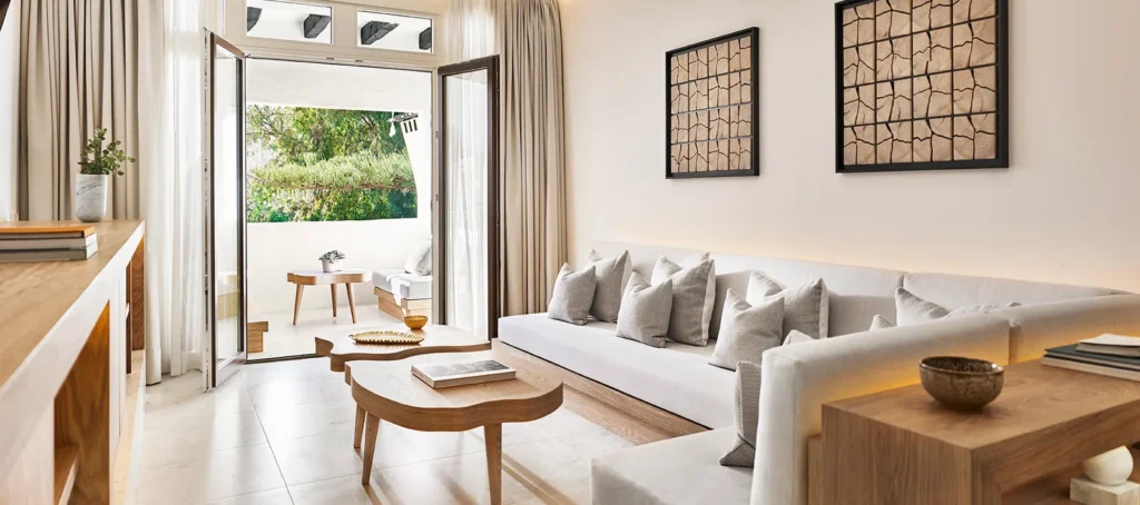 Nobu Hotel junior suite living area with minimalist design, neutral tones, wooden furniture, large sofa with cushions, and private balcony view.