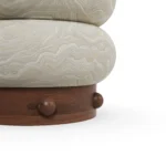 Details of Calie Stool by Nolita Harbour, sculptural seating stool in patterned velvet and matte walnut wood, composed of two rounded organic volumes inspired by natural stone formations, with a textured finish that reflects subtle mineral veining and refined tactile elegance. The image shows the lower left side.