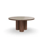 Roselle Dining Table, an elegant dining table by Nolita Harbour in stone, walnut, and brass studs, with a fluted pedestal base.