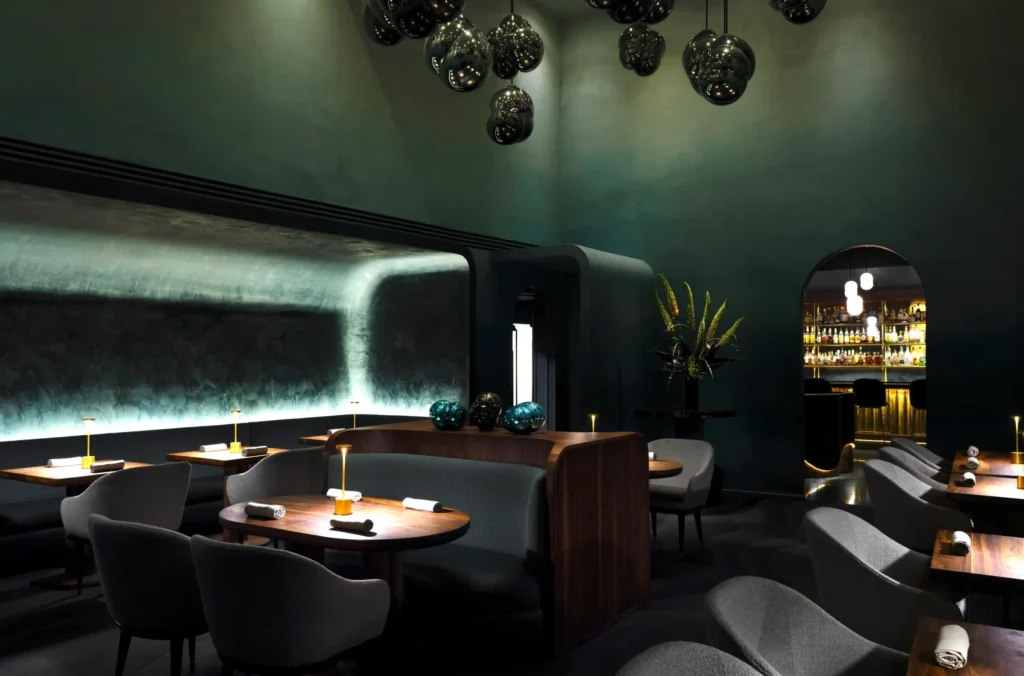 Minimalist luxury restaurant dining room with sculptural lighting, rich wood finishes, and intimate table arrangements, highlighting contemporary restaurant interior design and refined material craftsmanship.