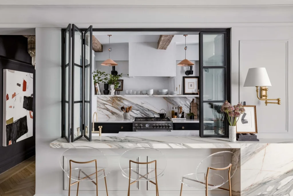 Elegant luxury kitchen with marble countertops, steel-framed interior windows, and custom cabinetry, designed by an international interior design studio.