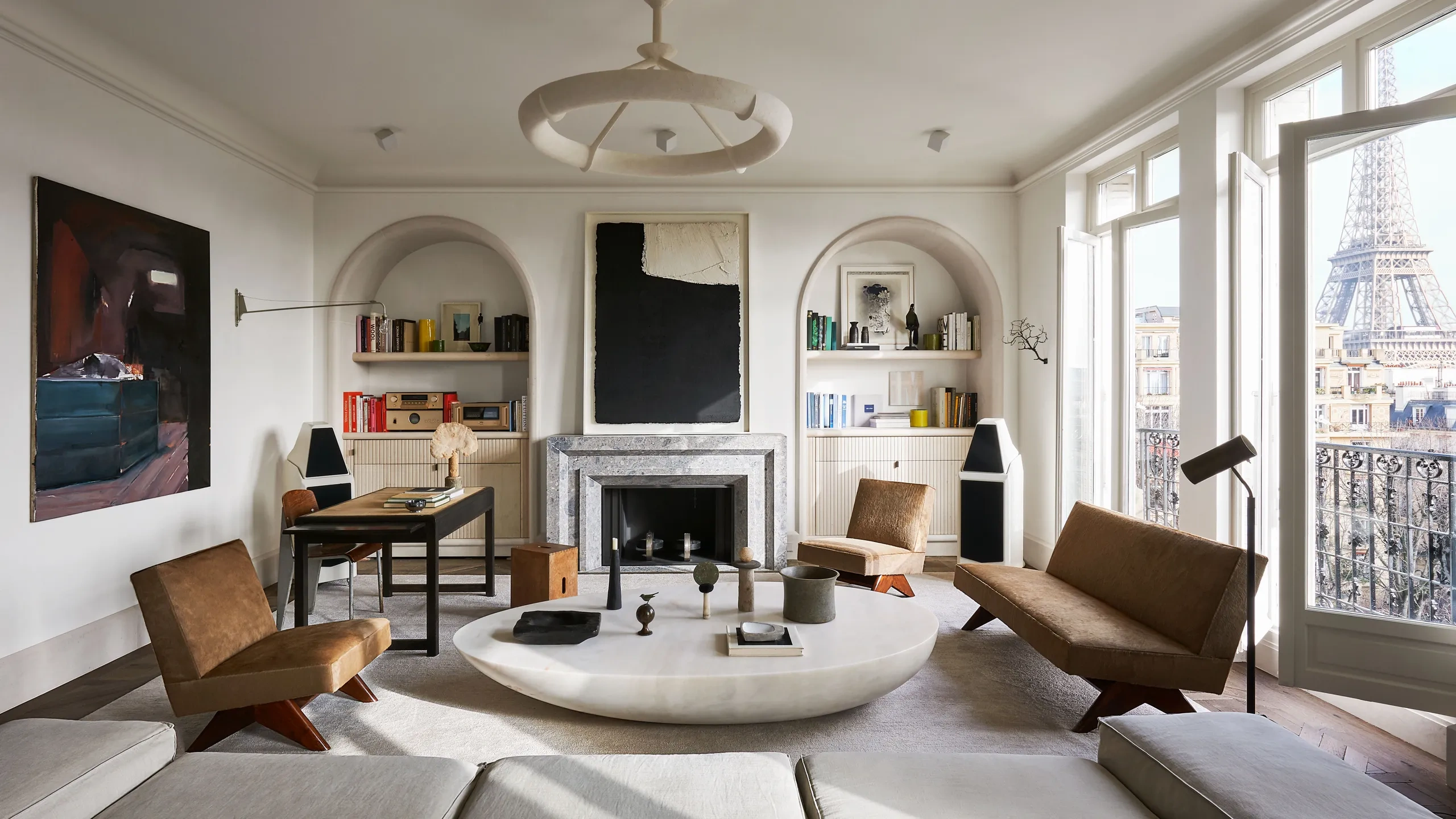Minimalist reinterpretation of a Haussmann apartment with marble fireplace, soft sculptural seating, and muted tones highlighting architectural purity.