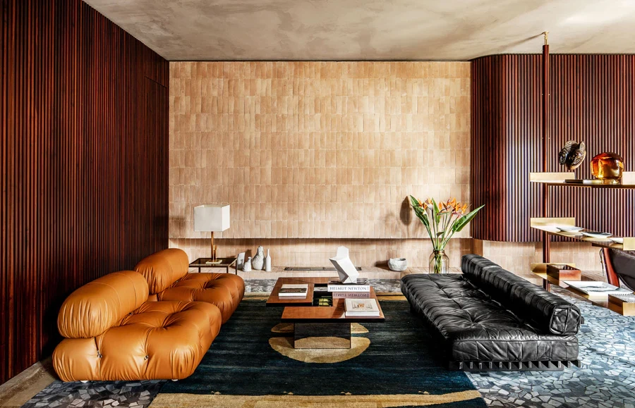 Mid-century modern living room featuring sculptural leather sofas, warm wood paneling, and a refined contemporary luxury interior aesthetic