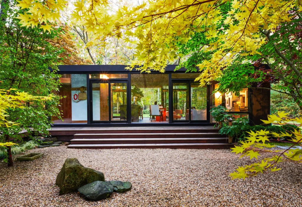 Mid-century modern residential architecture with floor-to-ceiling glass walls integrating the interior with a natural landscape