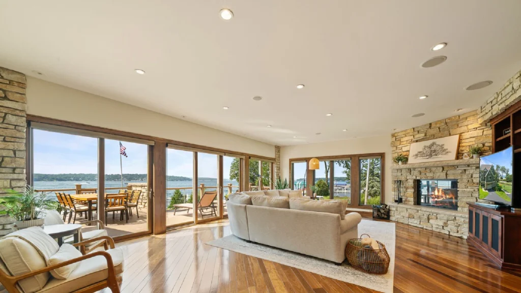 Luxury living room in a Geneva lakefront home with a low-profile neutral sofa positioned toward floor-to-ceiling windows overlooking Lake Geneva, illustrating refined living room seating arrangement and luxury waterfront interior design.