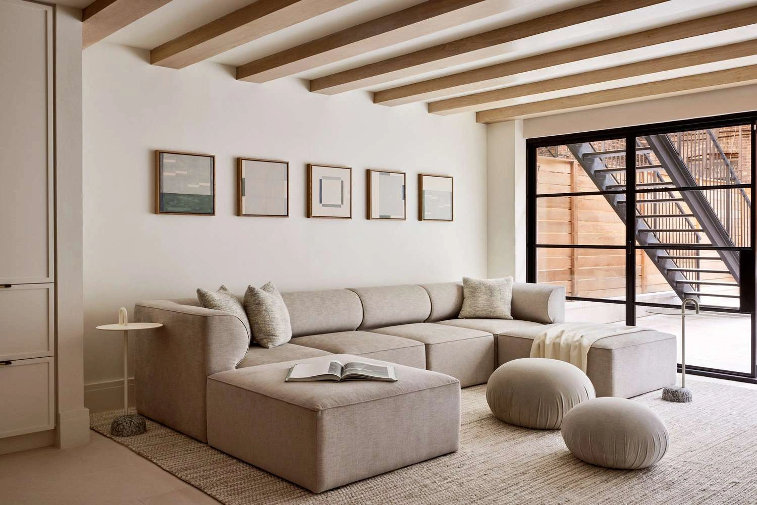Neutral living rooms showcasing layered neutral interior design with textured linen and bouclé seating, warm wood furniture and paneling, sculptural coffee tables, soft area rugs, marble fireplaces, and refined metal lighting accents—demonstrating depth and dimension in contemporary neutral interiors.