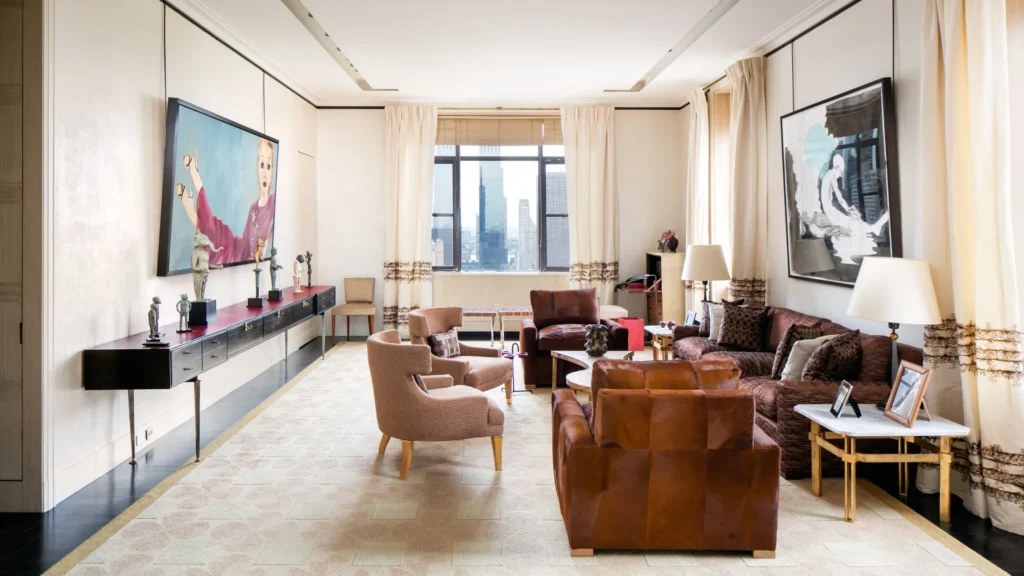 Elegant New York living room influenced by Peter Marino’s design philosophy, featuring symmetrical seating, curated art above a classical fireplace, and a bold red rug anchoring the space with architectural clarity.