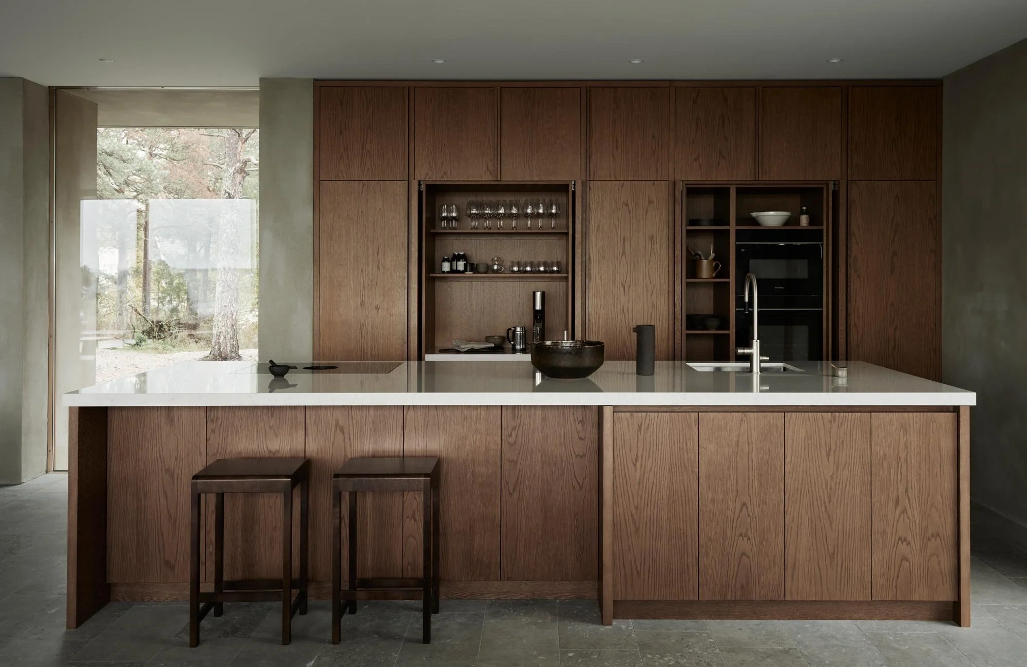 Elegant examples of concealed storage in high-end interiors, including a seamless wood-paneled kitchen with hidden cabinetry, a handleless minimalist kitchen with integrated appliances, a slatted wall concealing a flush hidden door, a softly illuminated walk-in wardrobe with built-in drawers and shelving, and a contemporary upholstered ottoman with hidden storage in a refined living room setting.