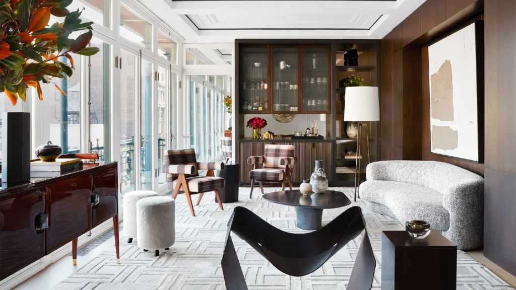 Luxury SoHo loft interior design in a historic New York loft featuring exposed brick walls, cast-iron columns, double-height industrial windows and expansive industrial loft living rooms styled with sculptural modular sofas, plush bouclé and leather seating, oversized area rugs, contemporary art, and warm ambient lighting balancing raw architecture with refined soft furnishings.