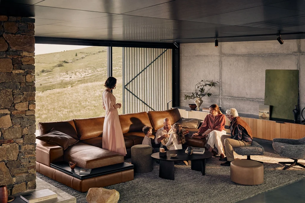 Flexible luxury living space designed for multi-generational use, combining custom leather seating, architectural concrete walls, and panoramic landscape views in a refined high-end interior design setting.