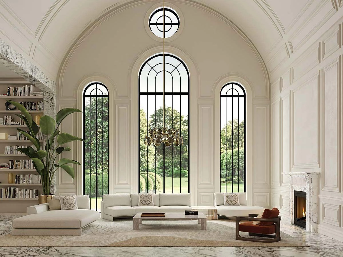 Elegant living room with tall arched windows showcasing a lush garden. Features a white sectional sofa, a marble fireplace, and a bookcase, creating a serene ambiance.
