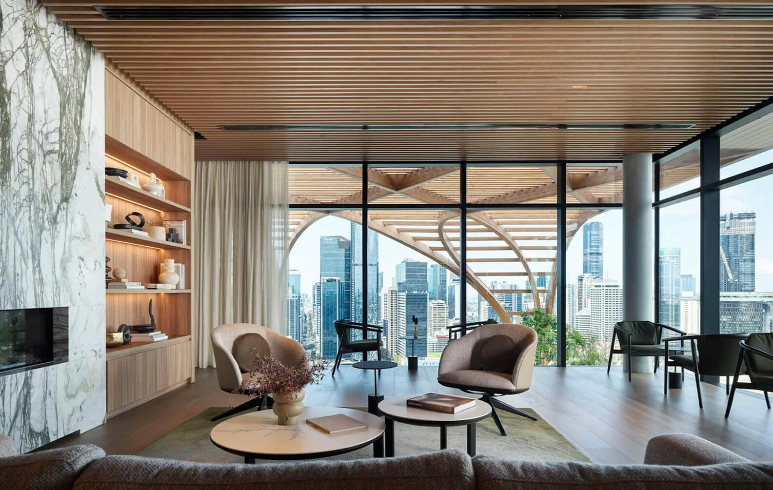 Modern living room with city views through large windows. Features sleek furniture, wooden ceiling, marble wall, and decorative shelves, creating a calm, sophisticated ambiance.