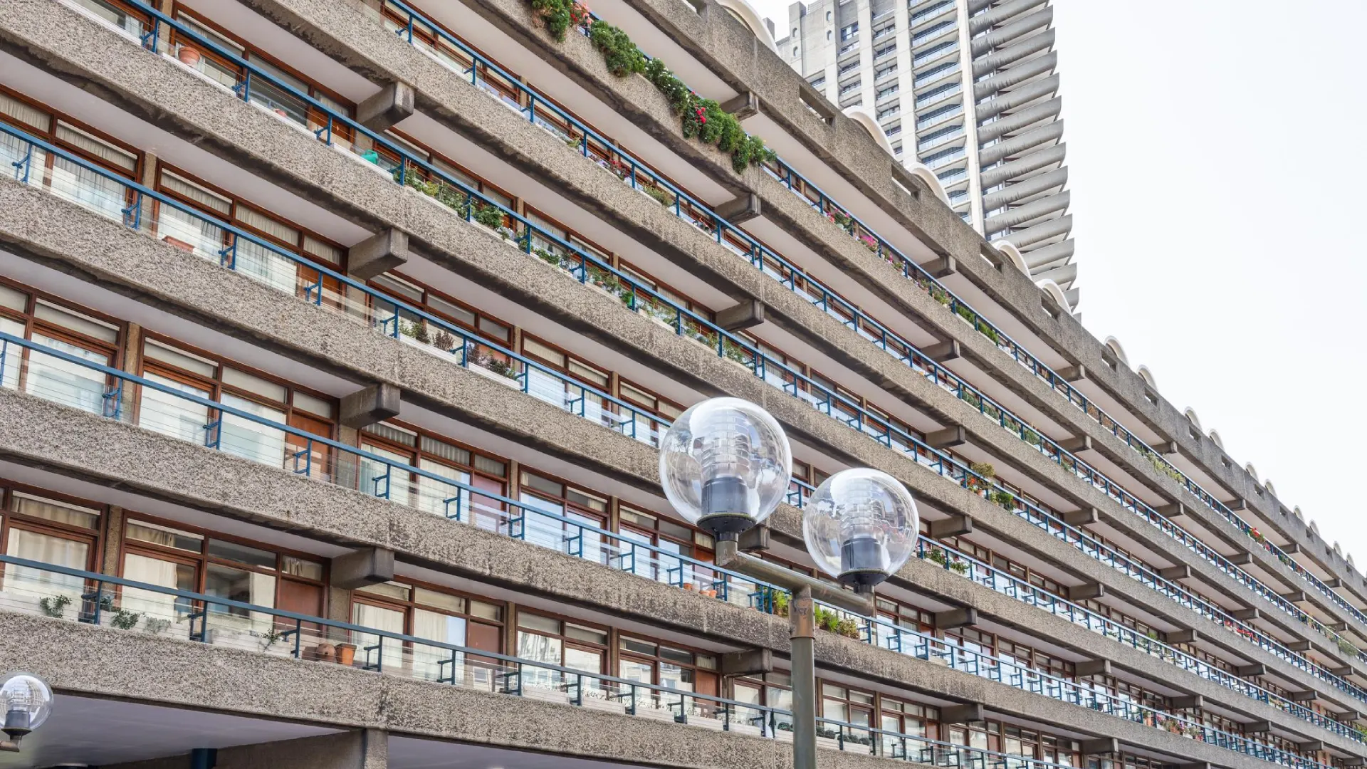 Barbican Estate brutalist apartments in London featuring split-level interiors, concrete architecture, landscaped terraces, and iconic modernist towers.