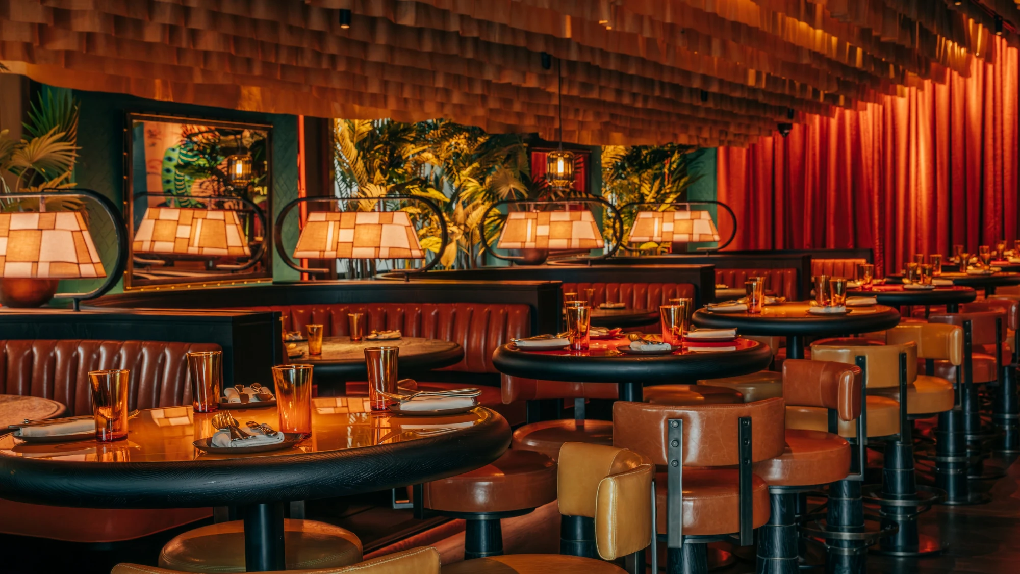 Luxurious restaurant interior with warm lighting, featuring leather booths, retro lamps, and elegant table settings. The ambiance is cozy and inviting.