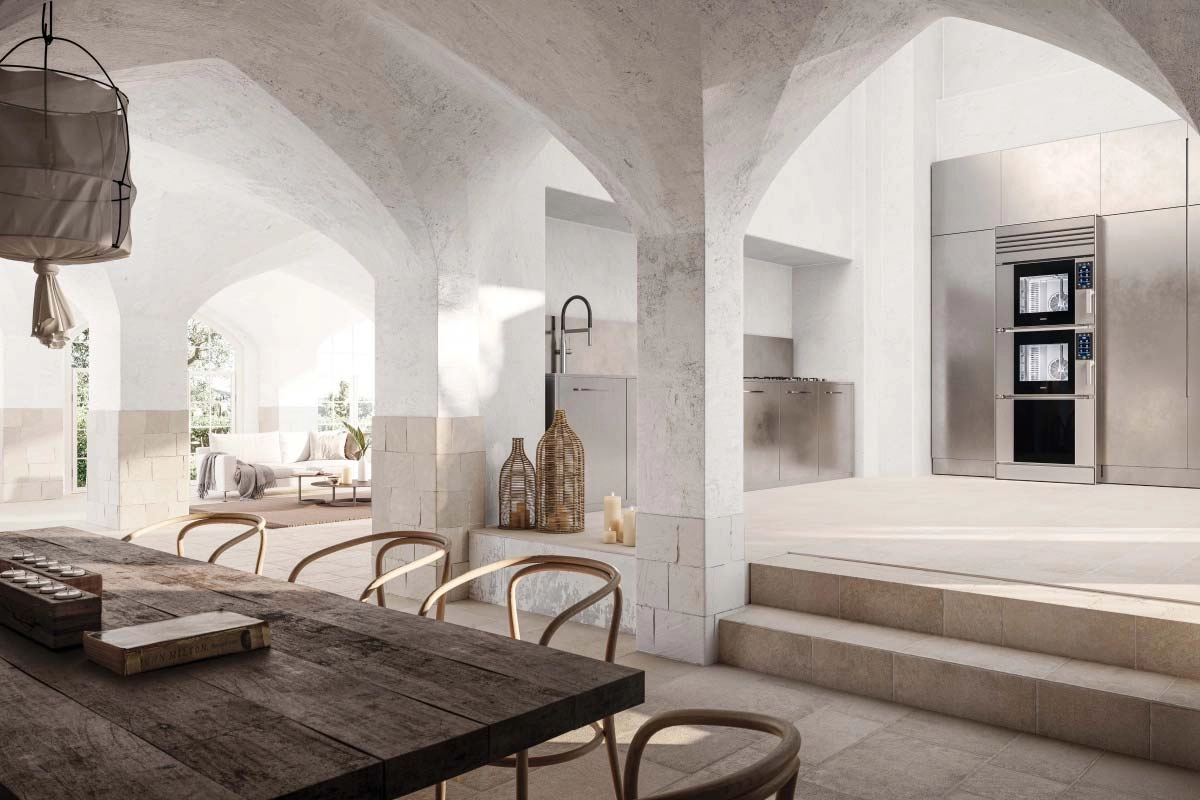 Spacious kitchen with arched ceilings, featuring a rustic wooden table and modern stainless steel appliances. Sunlight streams through large windows, creating a cozy, inviting atmosphere.