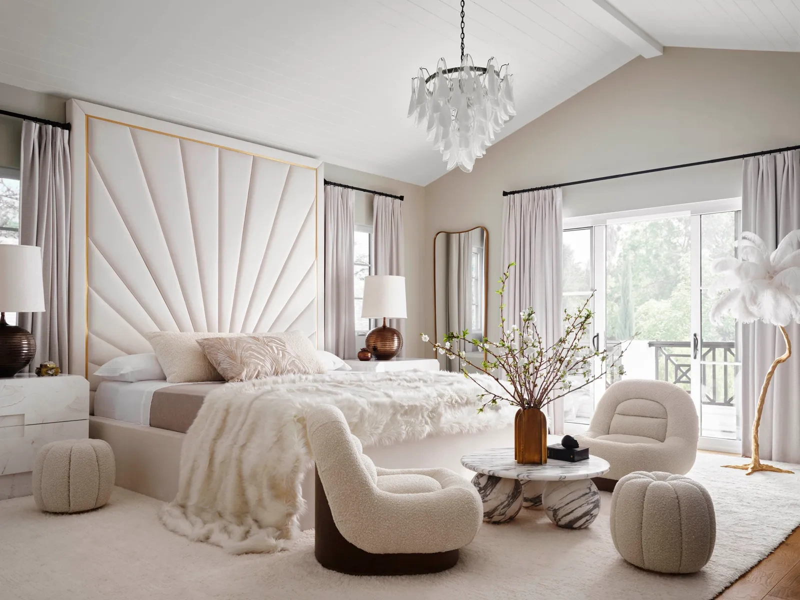 Luxurious bedroom with a large white fan-shaped headboard, plush bed, soft beige chairs, and a marble table, highlighting the usage of bouclé fabric for luxury interiors.