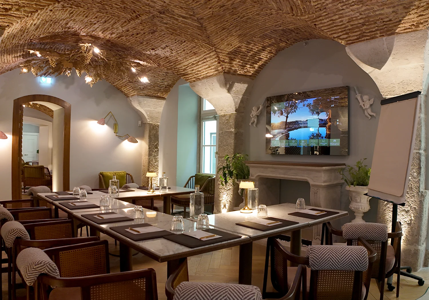 Chic meeting room with elegant stone arches, sophisticated table setup, and a large screen at Palácio Ludovice, one of Lisbon's best boutique hotels.