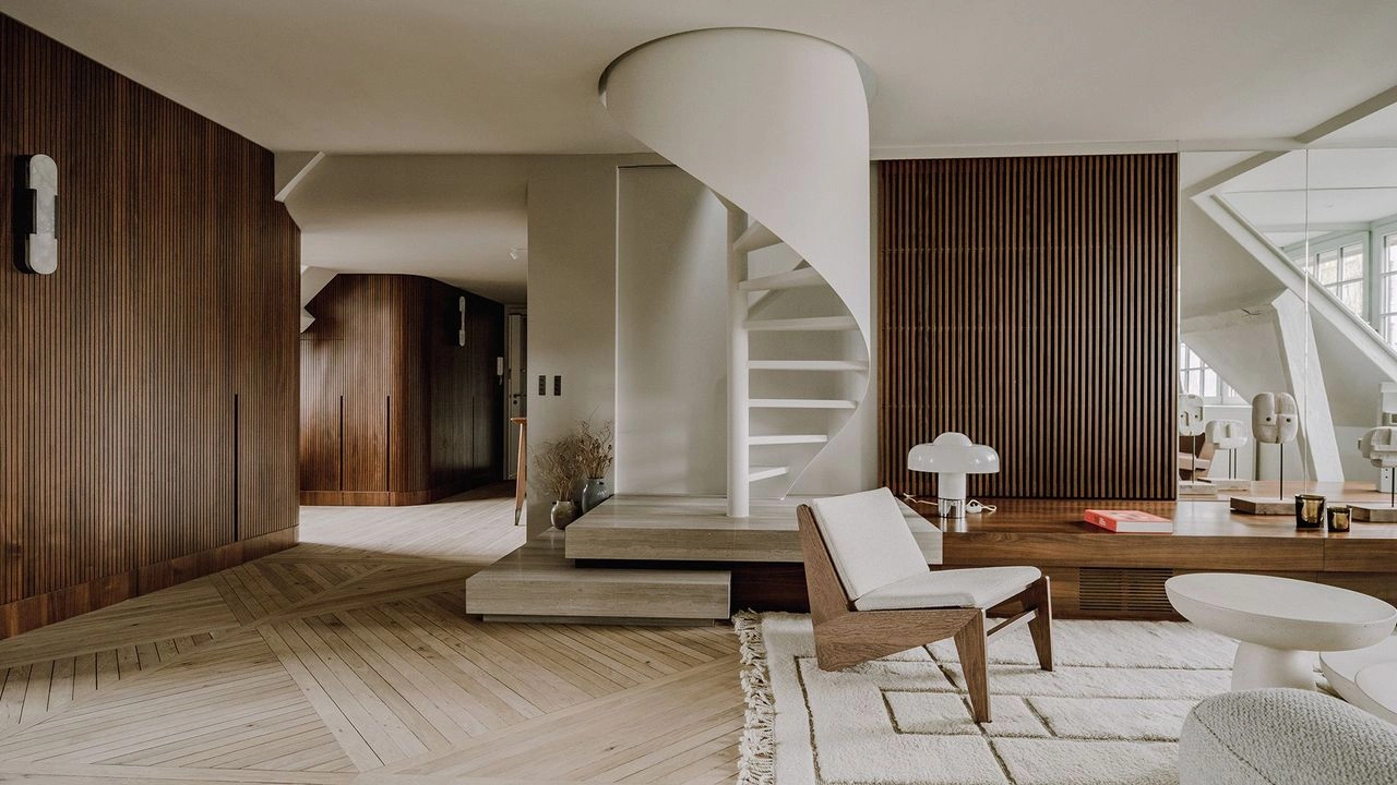 A modern living room with a white spiral staircase, wooden paneling, light wood flooring, and minimalist furniture. The room feels warm and inviting, environment present in mnimalist interiors.