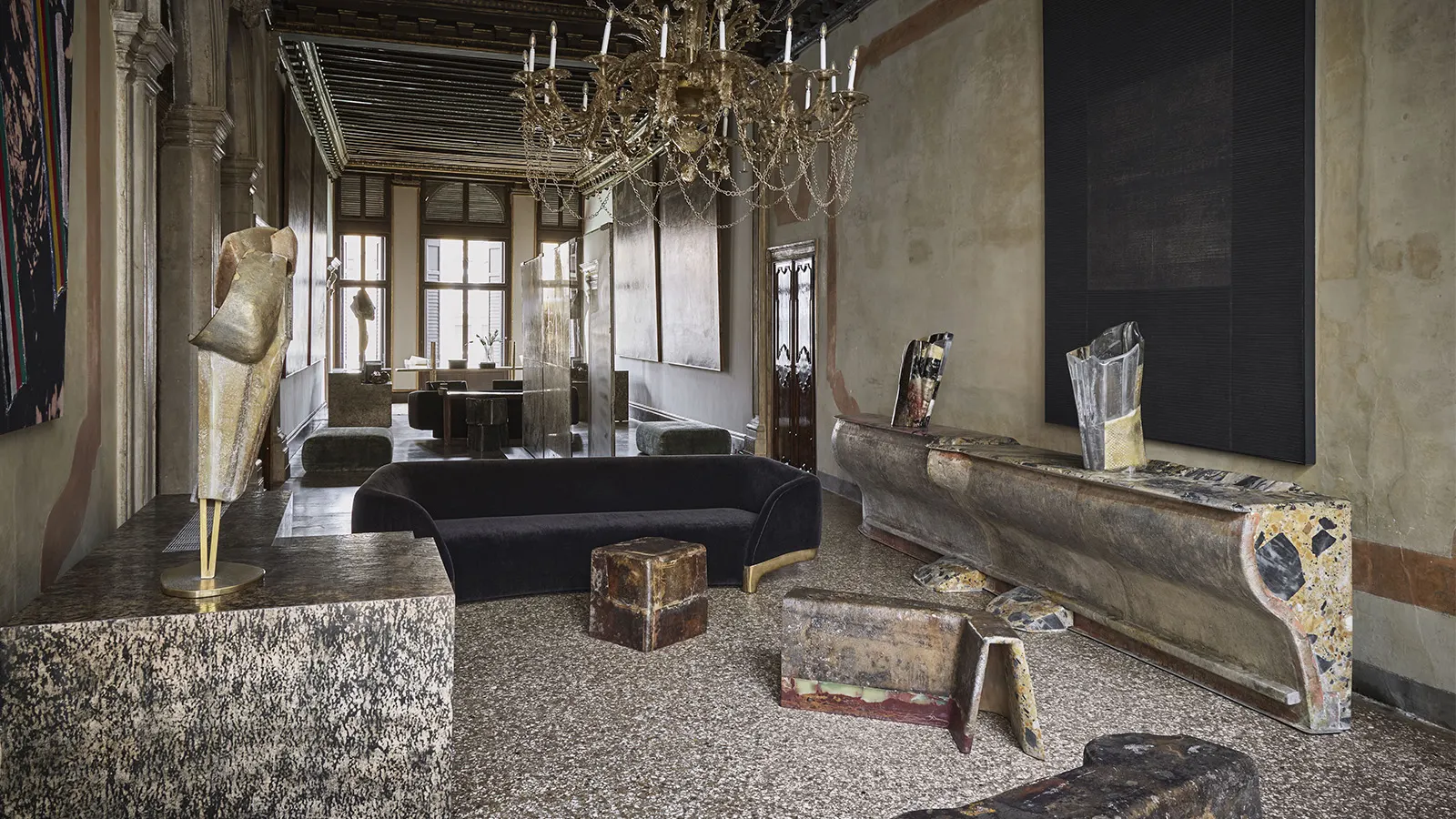 Luxurious room by Vincenzo de Cotiis with eclectic decor, featuring a black sofa, textured sculptures, large chandelier, and antique-style furniture. Elegant and artistic ambiance.