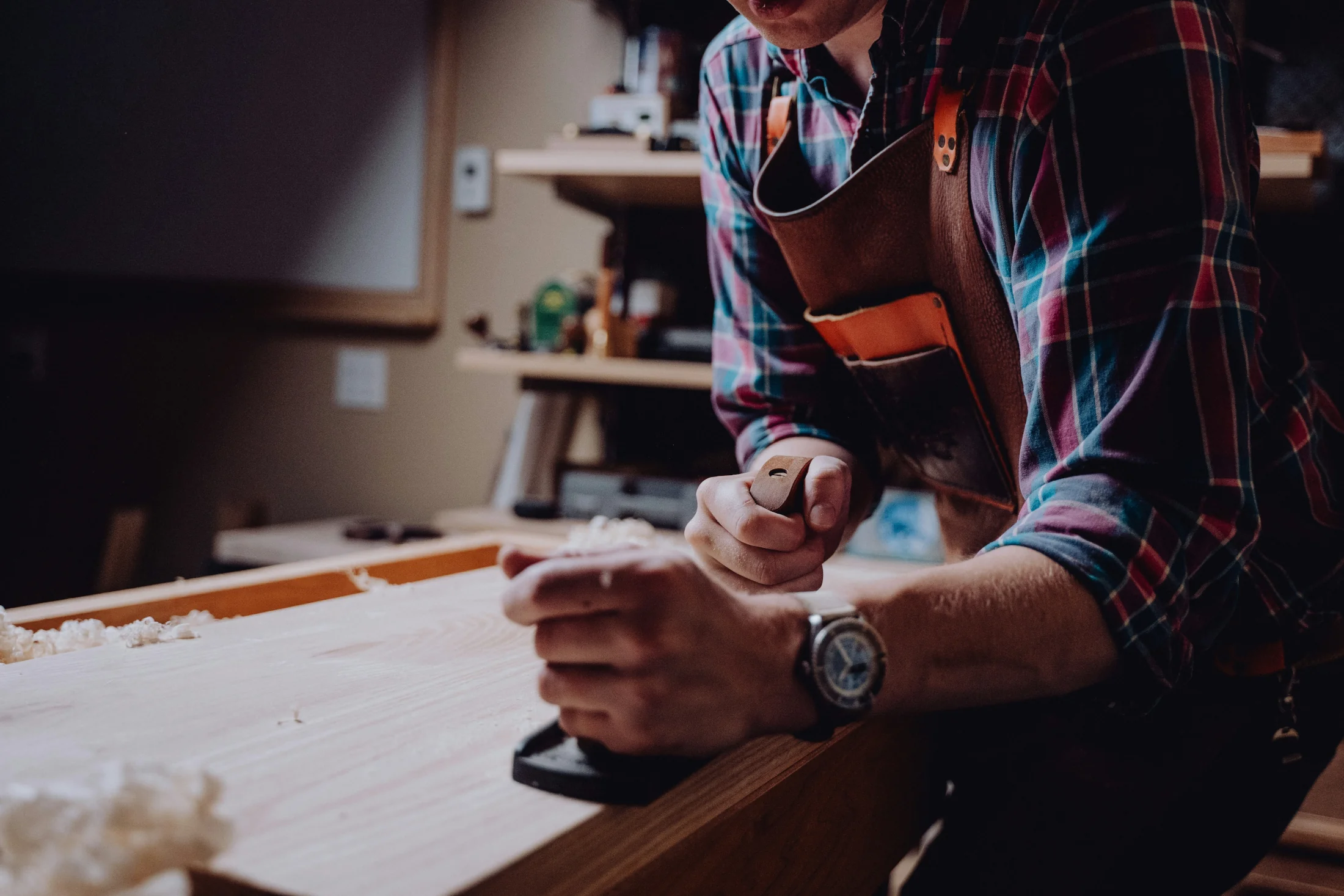 Furniture artisan hand-finishing a solid wood tabletop using traditional woodworking techniques.